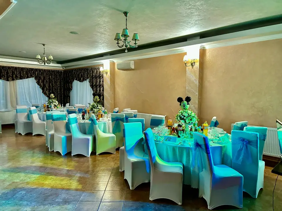 Sala în lumini turcoaz, cu huse albe pe scaune