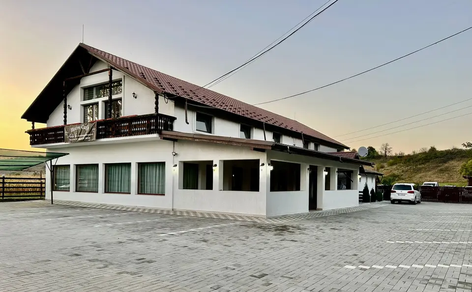 Fațada Bistro Cafe Events la apus, cu parcare pavată