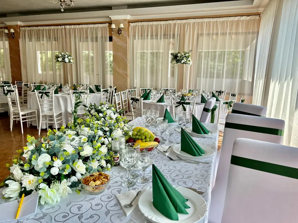 Masa mirilor cu aranjamente de flori albe și șervețele verzi, în sala Bistro Cafe Events