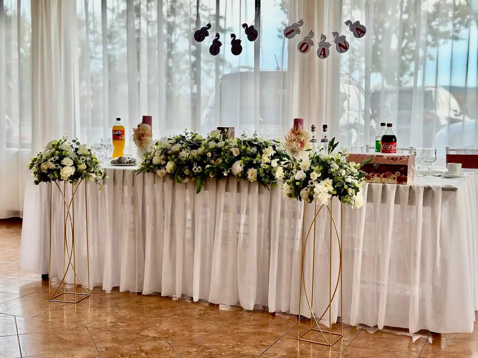 Masa principală decorată cu flori albe și draperie albă